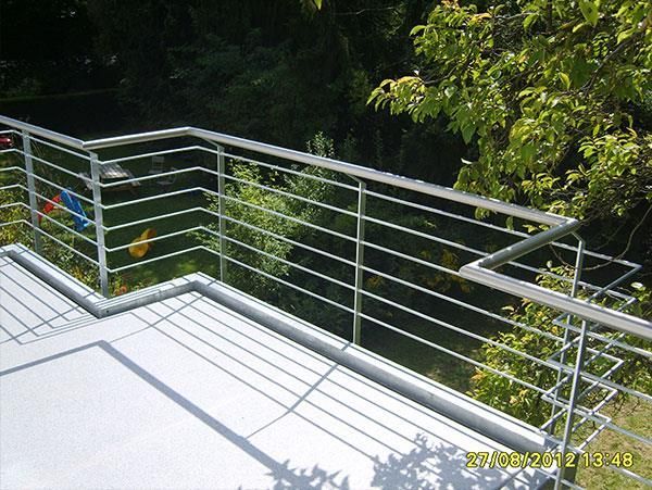 Ein Balkon mit einem Edelstahlgeländer, umgeben von Bäumen