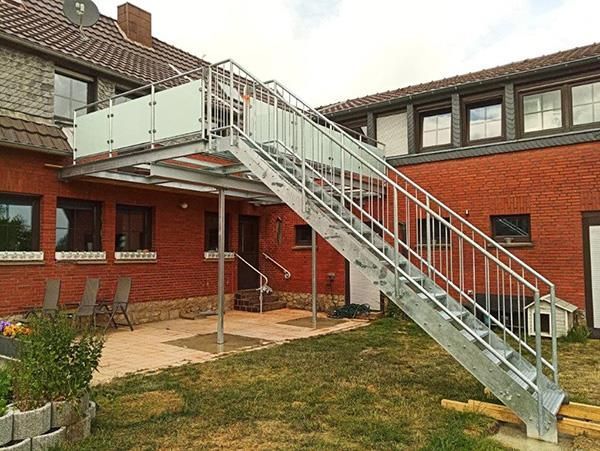 Eine Metalltreppe führt zu einem Balkon vor einem Backsteingebäude.