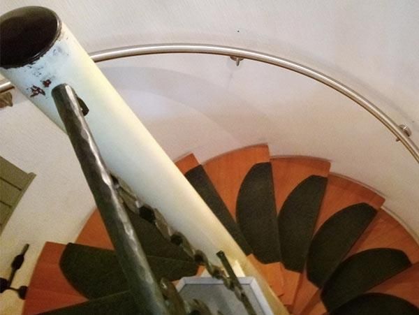 Eine Wendeltreppe mit weißem Geländer und schwarzen Stufen