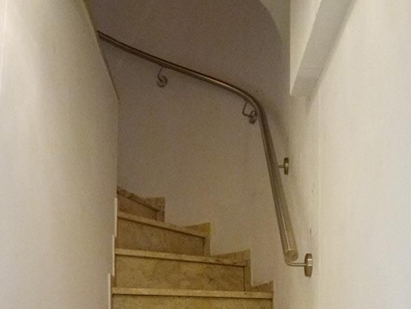 Eine Treppe mit Edelstahlgeländer und weißer Wand.