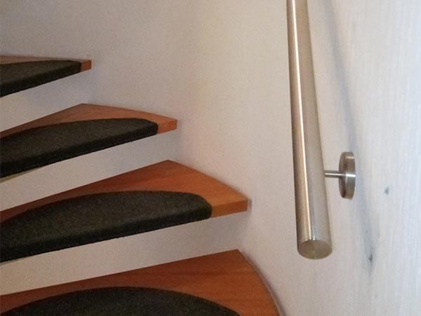 Eine Treppe mit Edelstahlgeländer und schwarzen Stufen