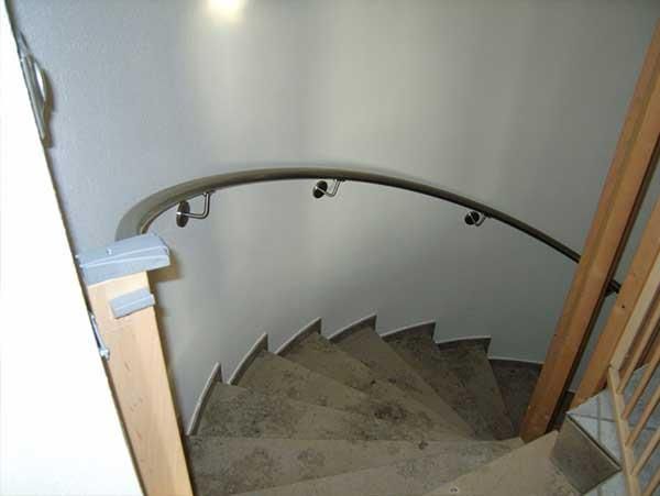 Eine Wendeltreppe mit Holzgeländer und weißer Wand