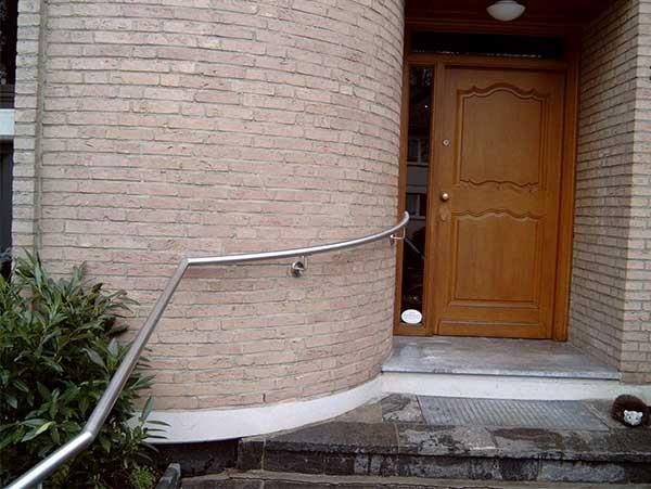 Ein Backsteingebäude mit einer Holztür und einem Edelstahlgeländer.