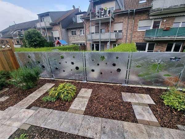 Ein Garten mit einem Zaun und einem Backsteingebäude im Hintergrund.