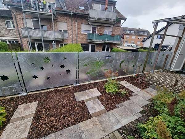 Ein Garten mit einem Zaun und einem Backsteingebäude im Hintergrund.