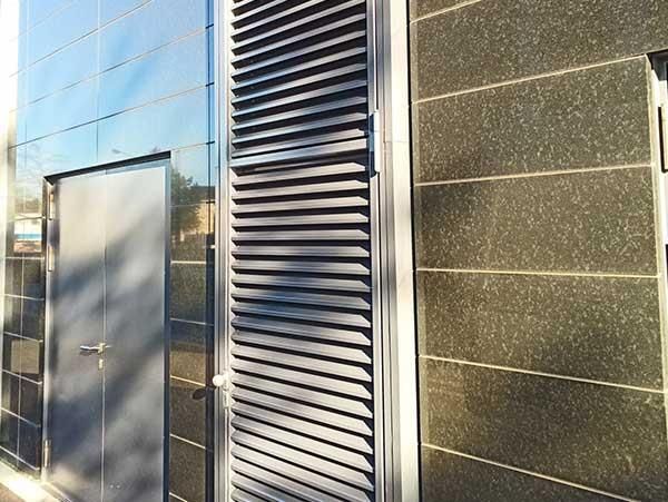 Ein Gebäude mit einer Tür und Fensterläden an der Seite.