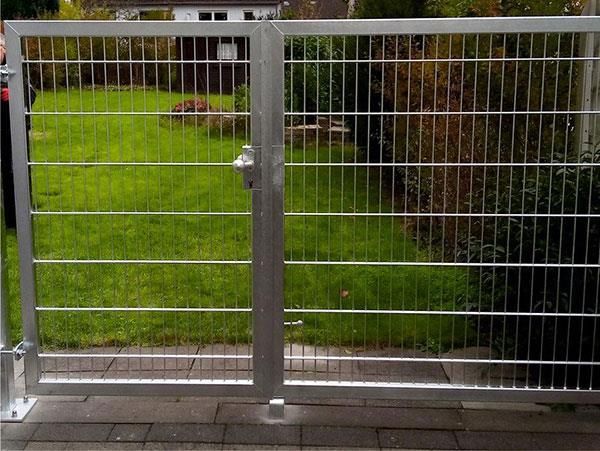 Ein Metalltor öffnet sich zu einem üppig grünen Hof.