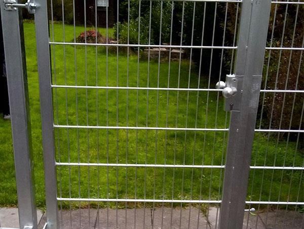 Ein Metalltor öffnet sich zu einem üppig grünen Hof.