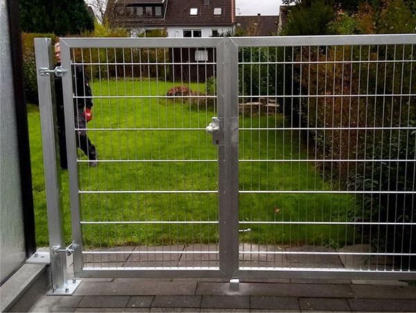 Ein Mann steht hinter einem Zaun in einem Hof