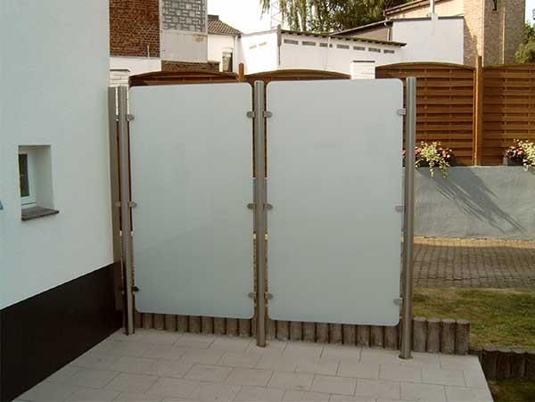 Ein weißer Zaun mit einem Holzzaun dahinter