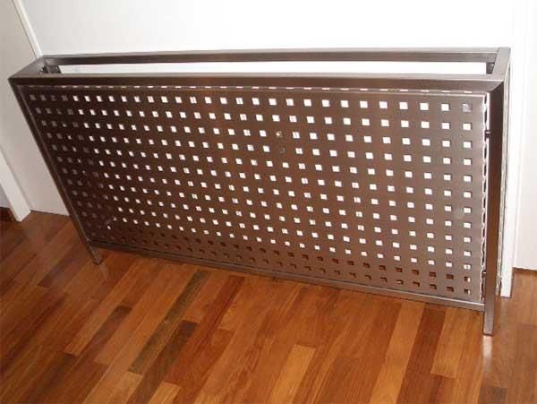 Eine Heizkörperabdeckung aus Edelstahl liegt auf einem Holzboden