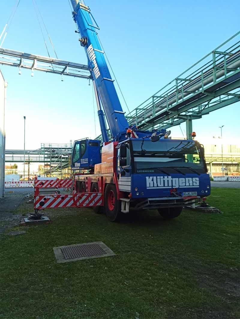 Ein blau-roter Kran steht auf einer Wiese.