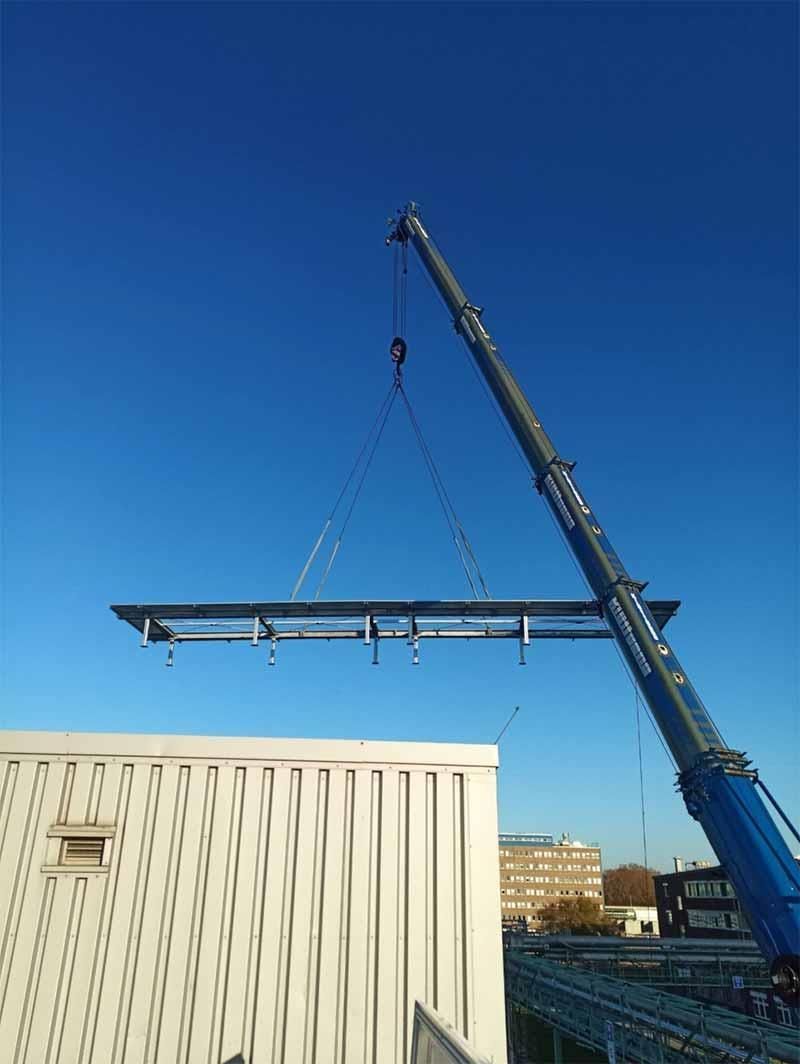 Ein Kran hebt ein großes Stück Metall über ein Gebäude