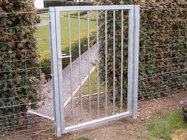 Ein Metalltor führt zu einem Weg hinter einem Zaun.