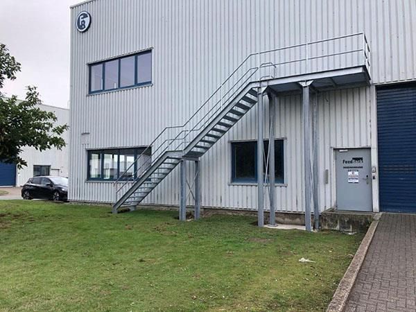 Ein Gebäude, zu dem eine Treppe hinaufführt, und ein davor geparktes Auto.