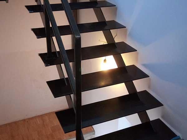 Eine schwarze Treppe mit einem Licht auf der untersten Stufe