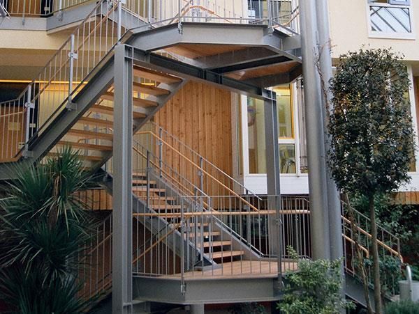 Eine Metalltreppe mit Holzstufen, die zu einem Gebäude hinaufführt