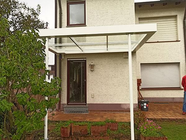 Ein weißes Haus mit einem Glasdach über der Eingangstür.