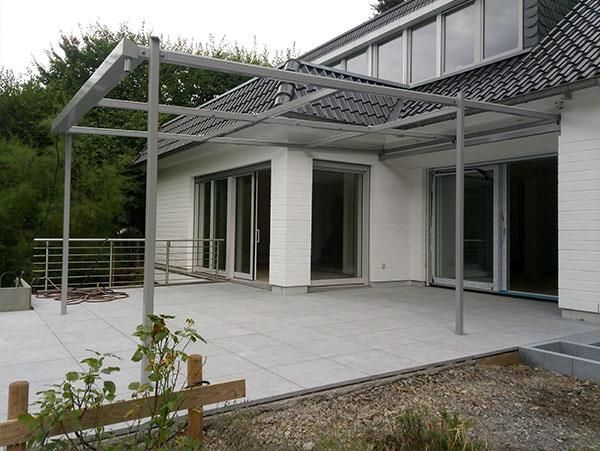 Ein weißes Haus mit einer Terrasse und einem Baldachin darüber.