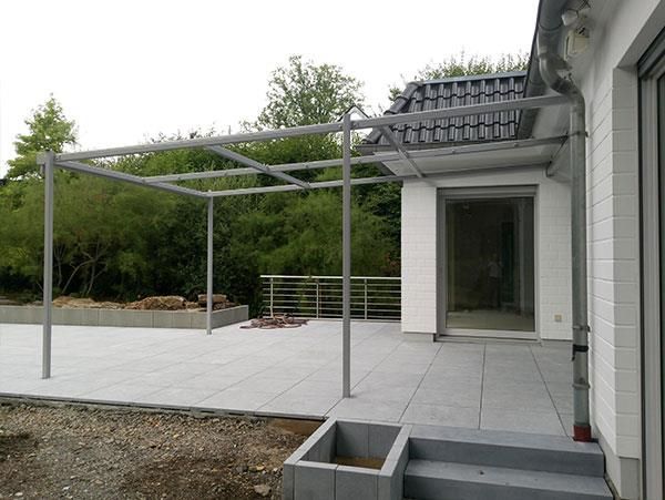 Ein weißes Haus mit einer Terrasse und einer Pergola davor.