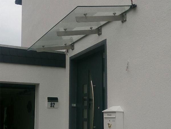 Ein weißes Gebäude mit einer schwarzen Tür und einem Glasdach darüber.