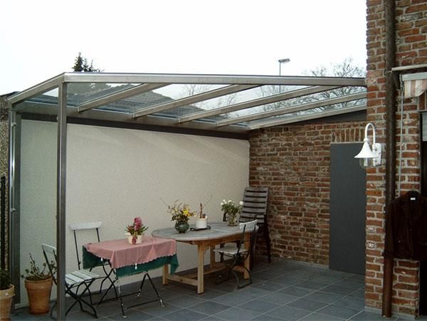 Eine Terrasse mit Tisch und Stühlen unter einem Glasdach