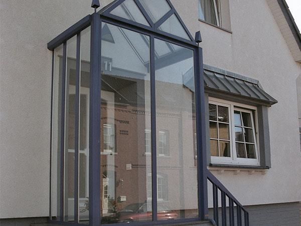 Ein weißes Haus mit einer Glasveranda und Treppen