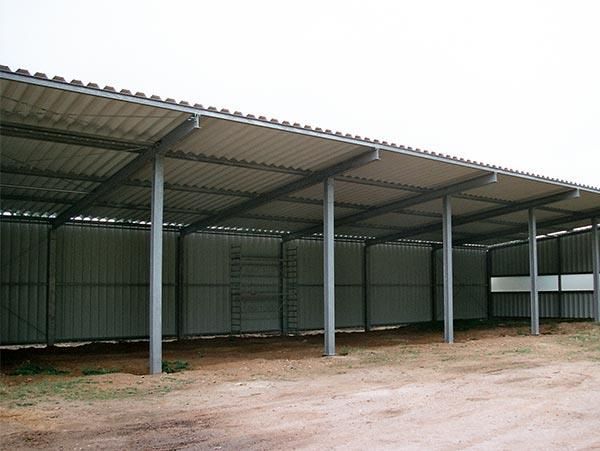 Eine große Metallkonstruktion mit Dach steht mitten auf einem Feld.