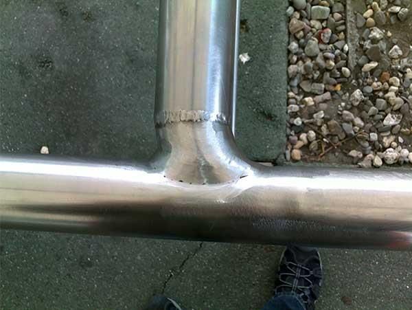 Eine Person steht neben einem Edelstahlrohr auf dem Boden.