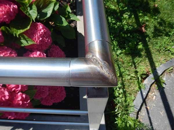 Ein Edelstahlgeländer mit rosa Blumen im Hintergrund