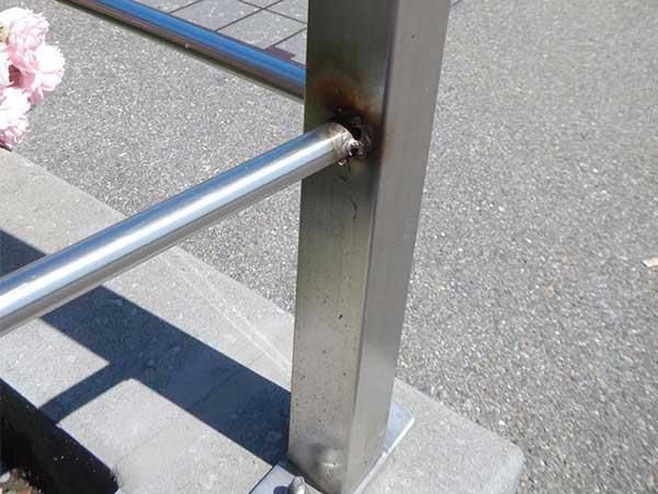 Eine Nahaufnahme eines Edelstahlgeländers mit einer Blume im Hintergrund.