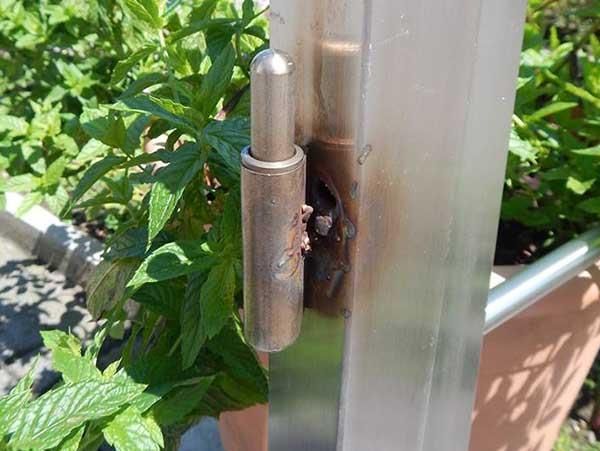 Eine Nahaufnahme eines Metallpfostens mit einer Pflanze im Hintergrund.