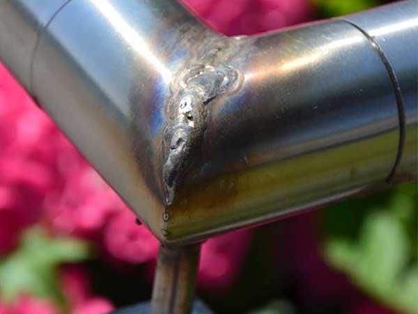 Eine Nahaufnahme eines Edelstahlrohrs mit Blumen im Hintergrund.