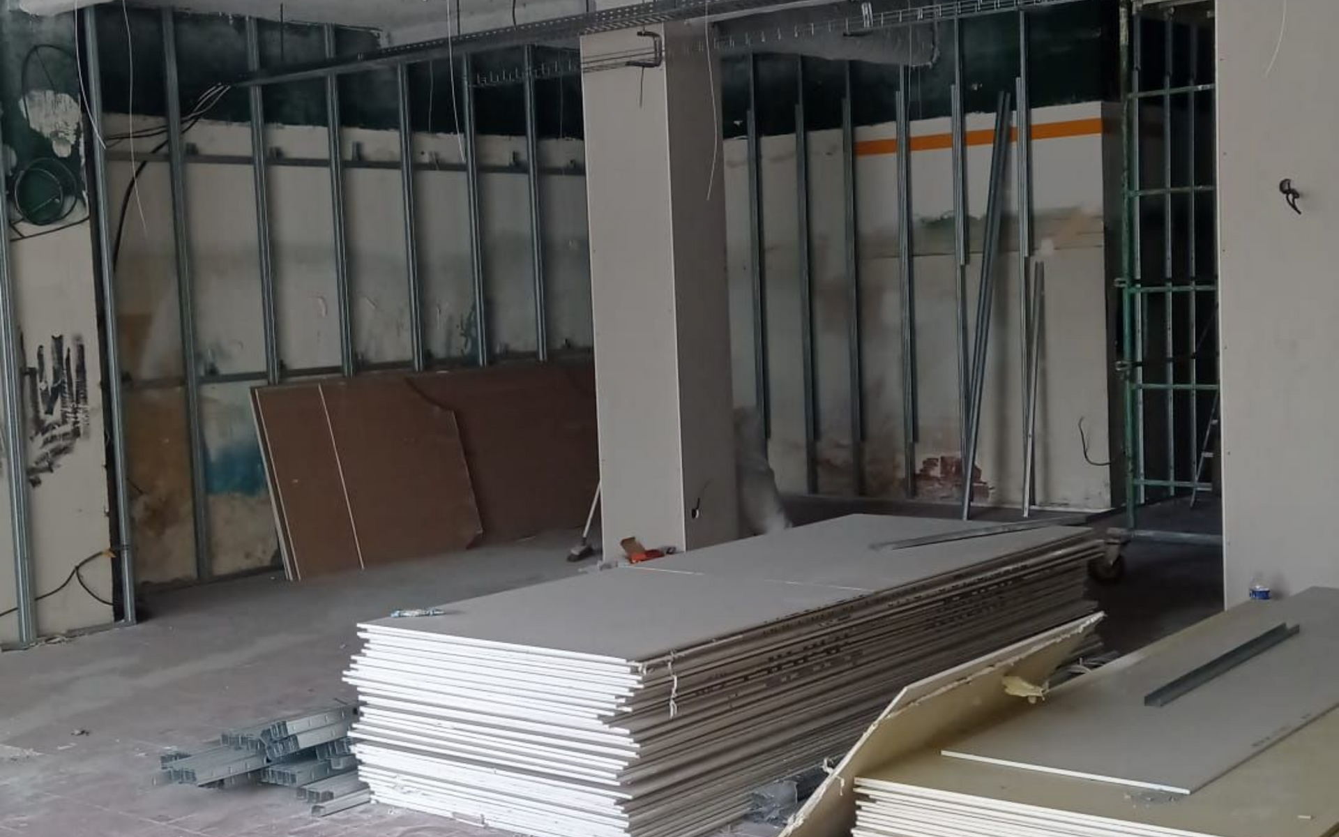 Chantier de construction intérieure : montants métalliques, plaques de plâtre et murs non finis.