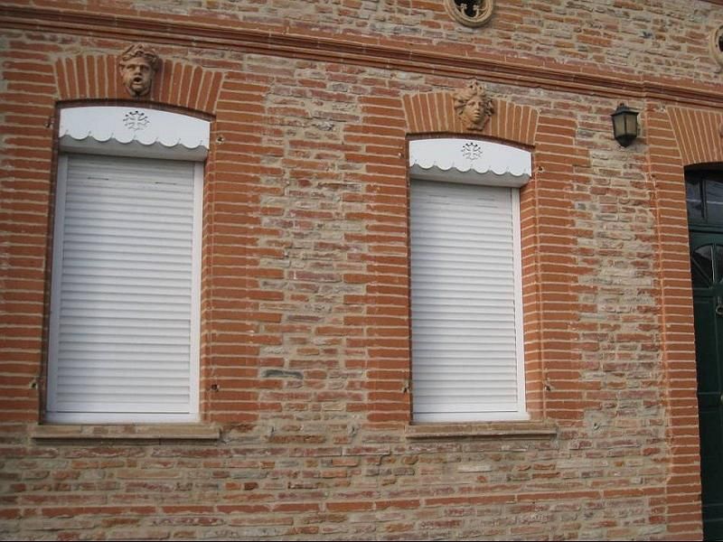 Photo de volets roulants blancs sur un mur en brique