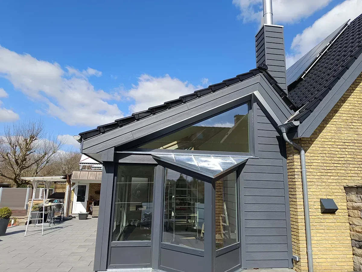 Ein graues und gelbes Gebäude mit einem modernen Glasanbau unter blauem Himmel.