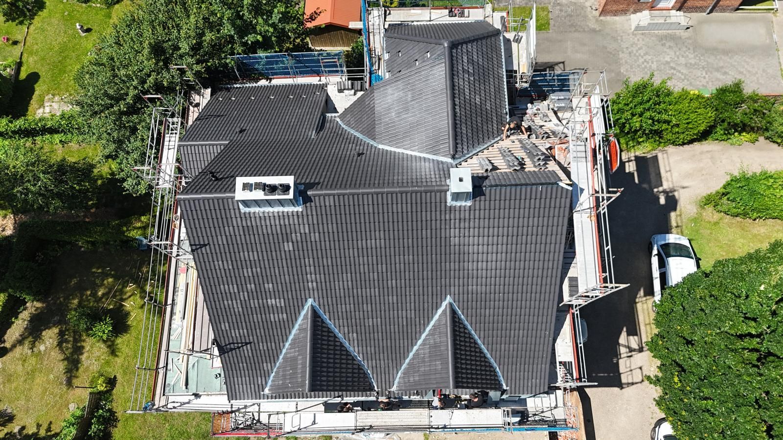 Reinigung eines verschmutzten roten Ziegeldachs mit einer Bürste mit langem Stiel.