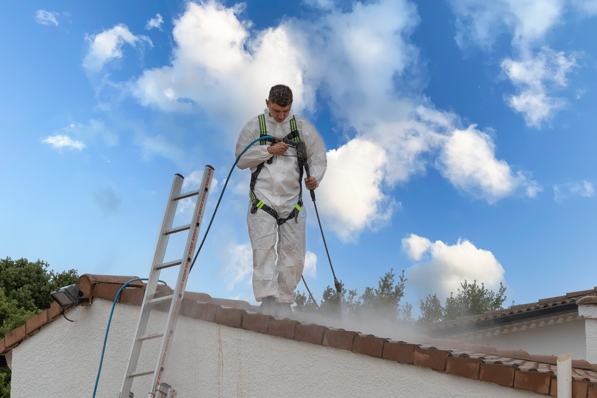 Un artisan en plein nettoyage d'une toiture