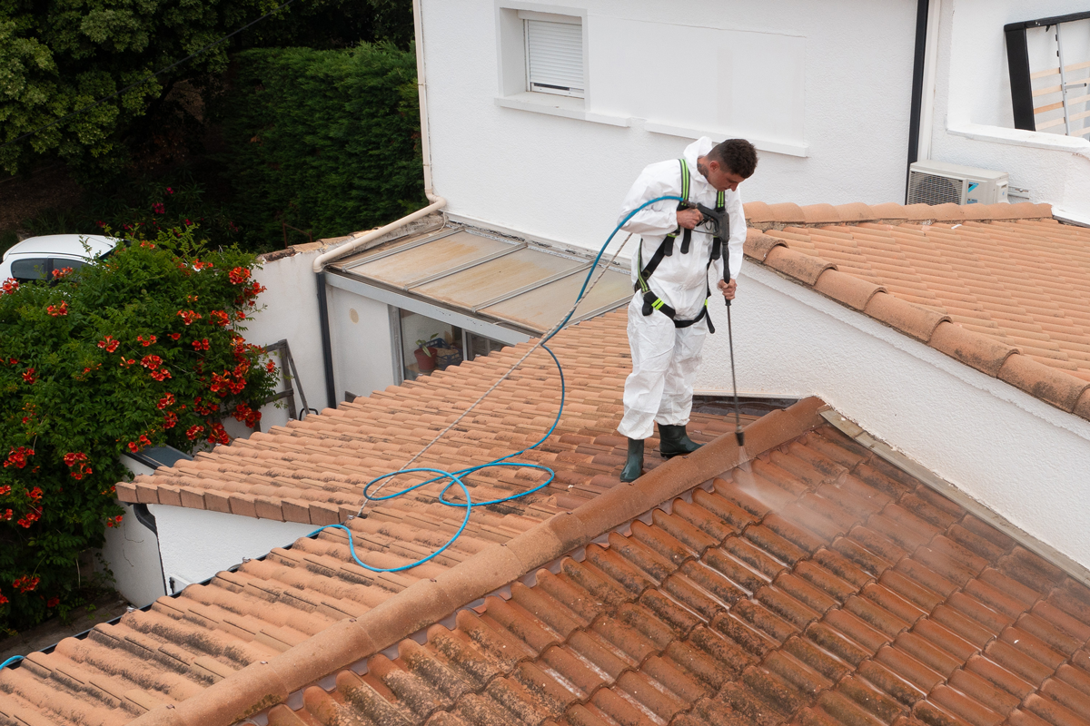 Un homme qui nettoie une toiture pleine de mousse