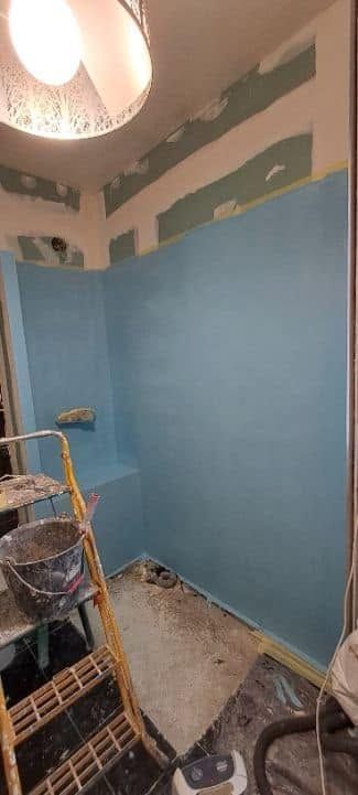 Petite pièce en cours de rénovation, avec des murs peints en bleu, des outils éparpillés et un luminaire suspendu