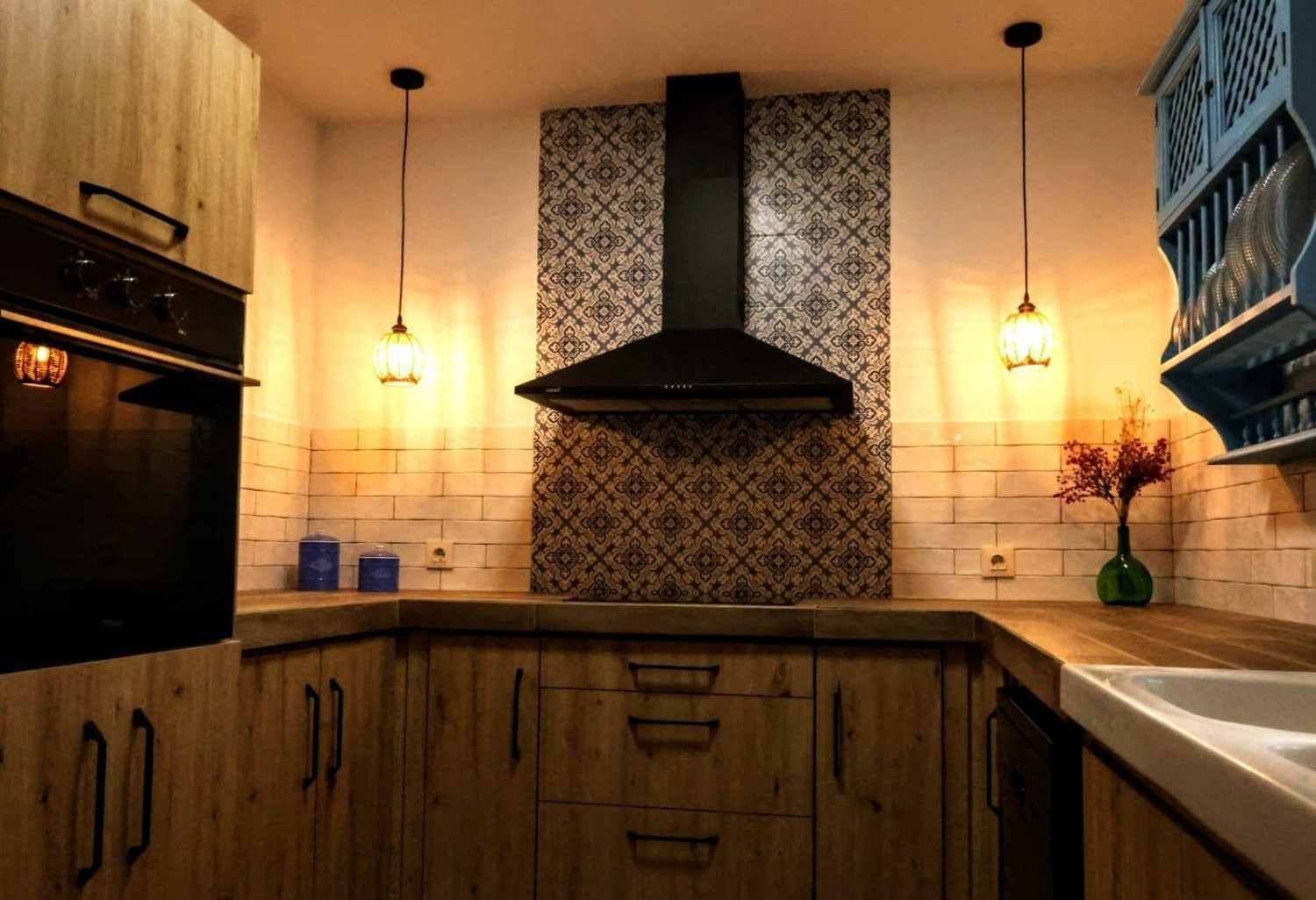 Sala de estar con pared de piedra, vigas de madera, mueble rojo y sofá azul.