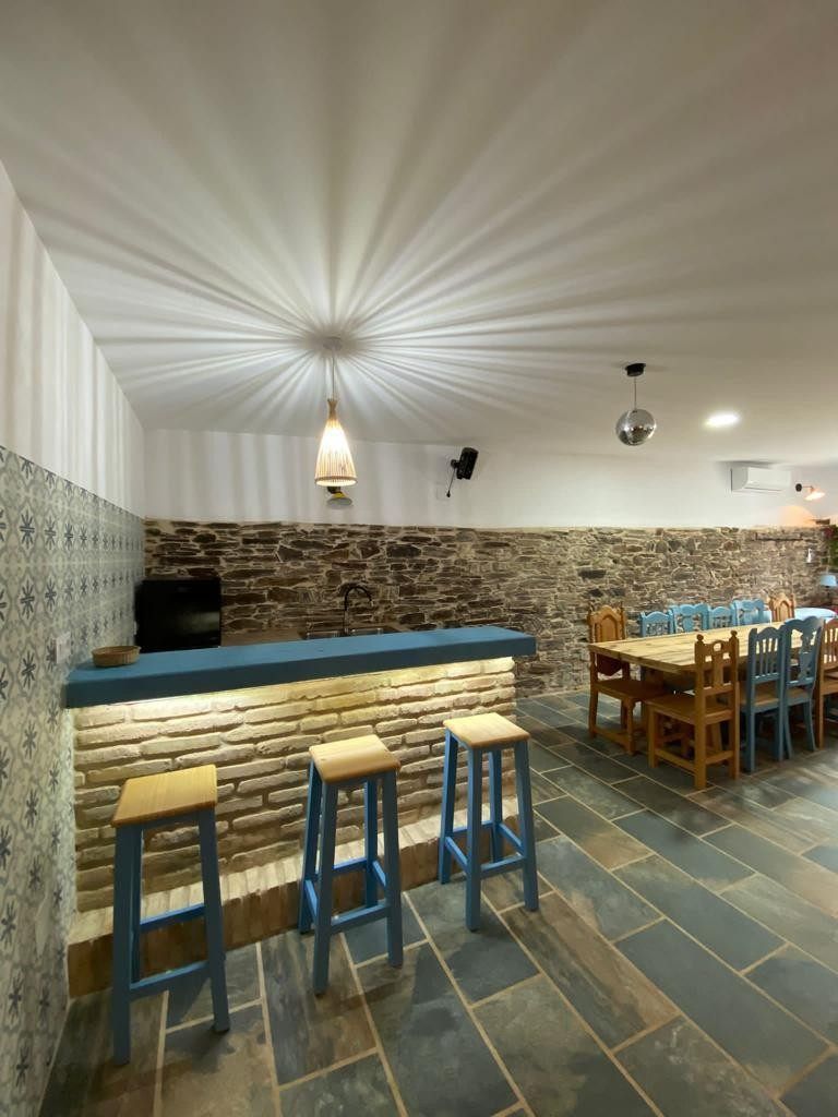 Acogedor interior de bar con suelo de baldosas estampadas, barra de madera, taburetes y mesas de comedor.