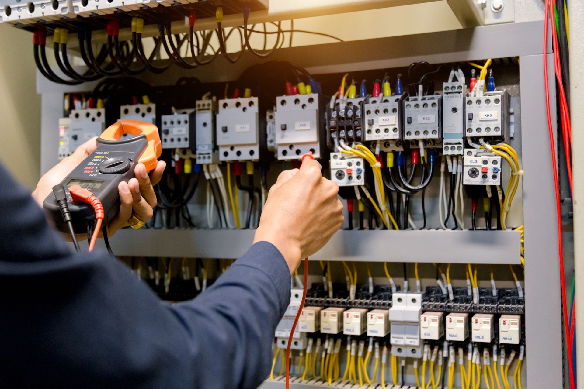 Un homme contrôlant la tension du courant électrique dans un tableau de disjoncteur 