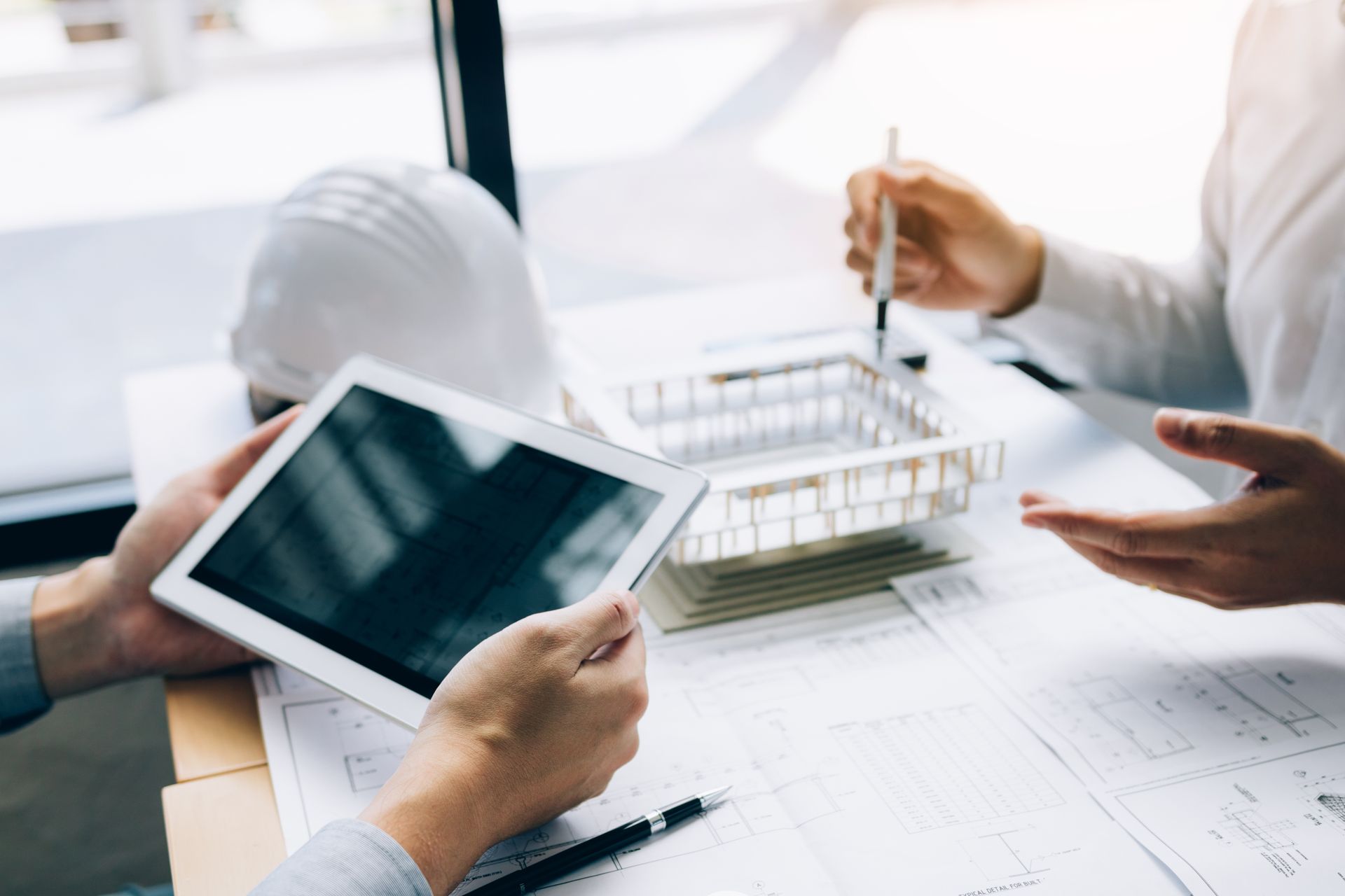Deux hommes discutant à un bureau sur lequel se trouve un plan d'architecte