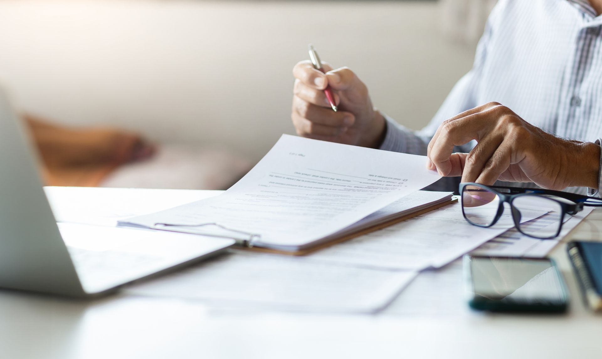 Homme assis à un bureau prenant des notes sur un ensemble de documents