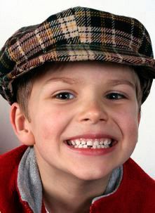 Un niño pequeño que lleva un sombrero a cuadros sonríe para la cámara.