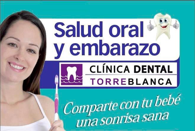 Una mujer sostiene un cepillo de dientes frente a un cartel que dice salud oral y embarazo.