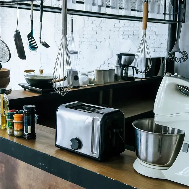 Encimera de cocina con tostadora, batidora y utensilios colgantes.