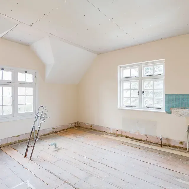 Reforma de habitación con suelos de madera a la vista, ventanas blancas y paredes claras.
