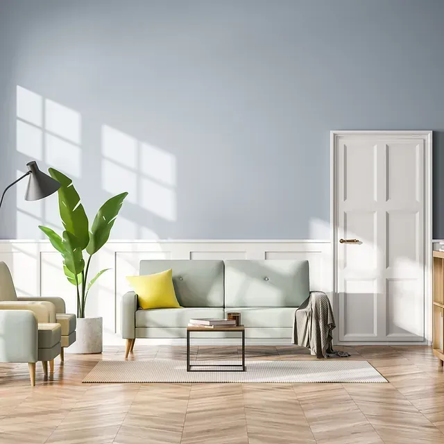 Una sala de estar moderna con paredes de color azul claro, un sofá verde, un sillón y una gran planta en maceta.